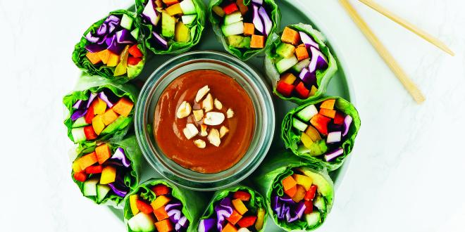 Colorful veggies wrapped in lettuce, positioned vertically around a dish of hoisin sauce.