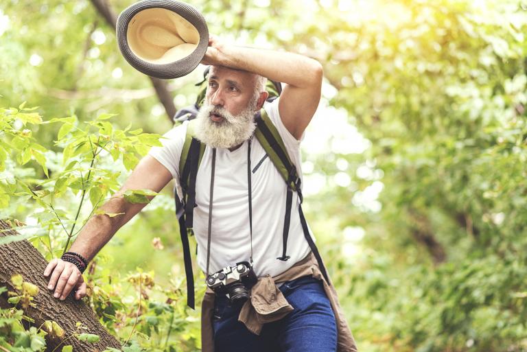 a healthy-looking man feeling exhausted on a hike in the woods