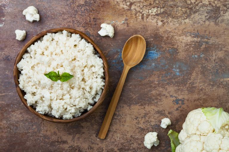 A wooden bowl filled with cauliflower rice.